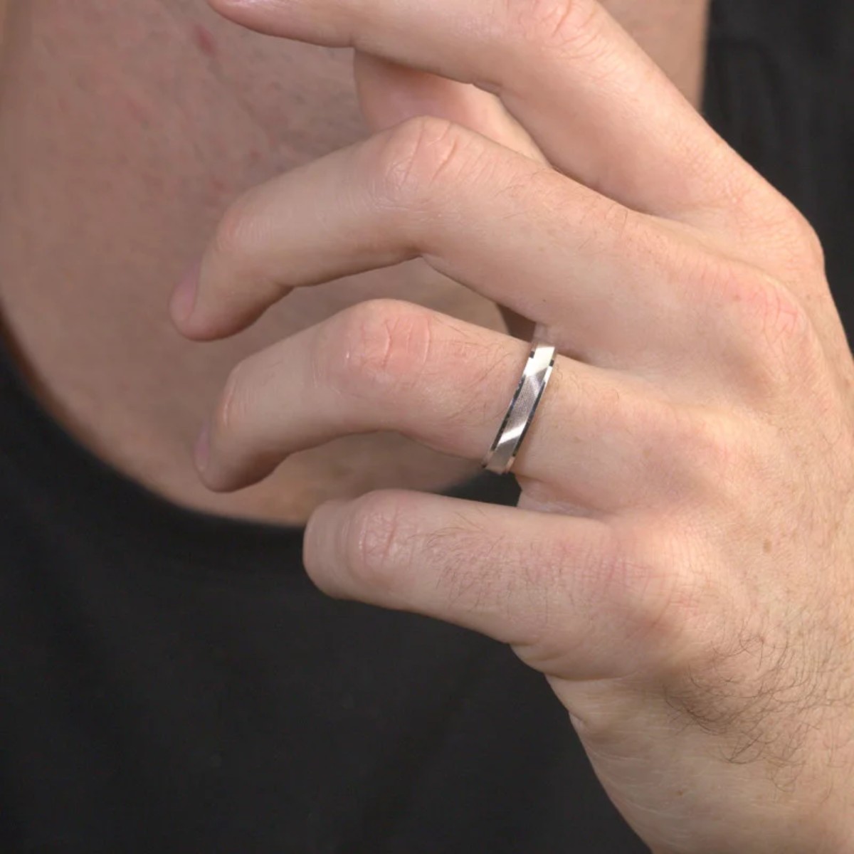 Gros plan sur une main masculine portant une bague en métal argenté à l’annulaire gauche – illustration de la signification des bagues pour homme selon les doigts